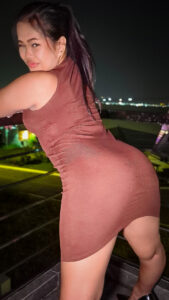Brandy B leans against roof top balcony in short dress