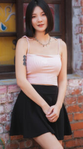 Xiaoba stands pretty against brick will in sexy black skirt
